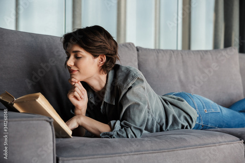 Fotografie Image of brunette cute pleased woman reading book and smiling