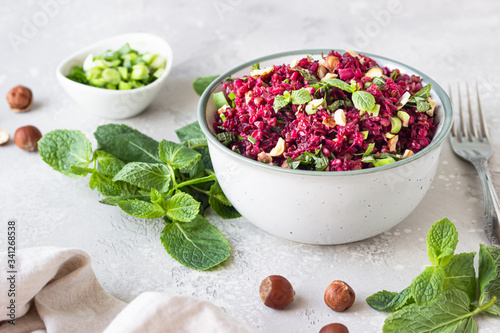 Warm buckwheat  beetroot  nuts and herbs salad  light grey concrete background. Vegetarian and vegan food. Healthy food concept. 