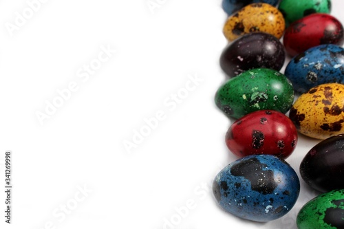 Frame of multi-colored quail eggs. Multi-colored quail Easter eggs on a white background. A line of multi-colored eggs is located on the right on a white background with place for text.