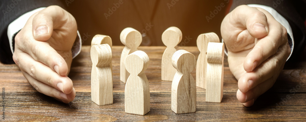 Businessman defending his team with a gesture of protection. Care for employees. Life insurance. Security and safety in a business team. Human resources. Social protection. Wooden figures - obrazy, fototapety, plakaty 