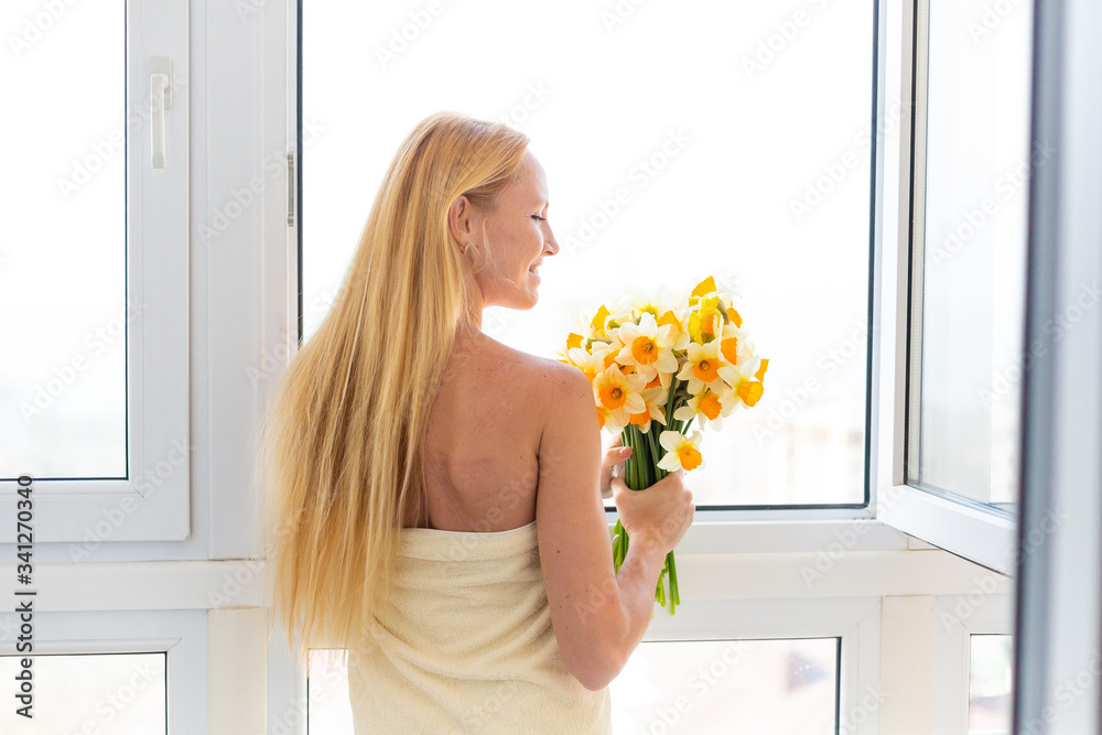 Fotografie Blonde model with narcissus by the window