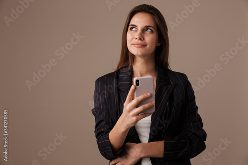 Photo of pleased businesswoman smiling and using cellphone