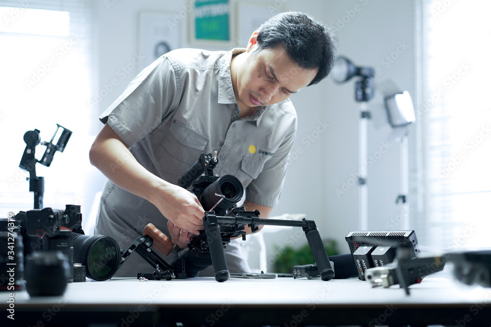 An Asian man is setting up a camera rig An Asian man is setting up a camera rig