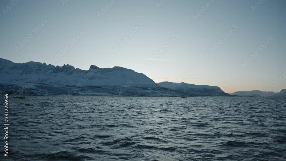 Small boats searching orca and humpback whale near fjords of Tromso in winter. Dark Blue water and mountains. Exclusive documentary footage Filmed RED camera during a scientific expedition to Norway Small boats searching orca and humpback whale near fjords of Tromso in winter. Dark Blue water and mountains. Exclusive documentary footage Filmed RED camera during a scientific expedition to Norway