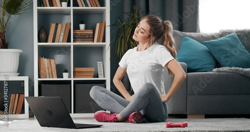 фотографія Young lady sitting with folded legs and inclined head on floor warming up before