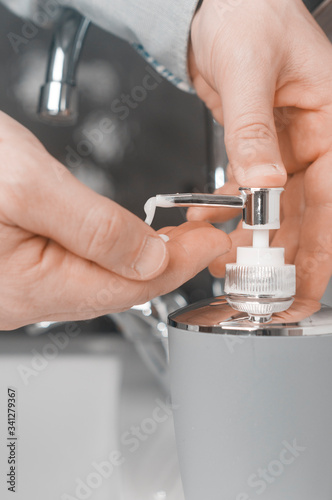 Hand washing concept: man in shirt soap his hands through a soap dispenser