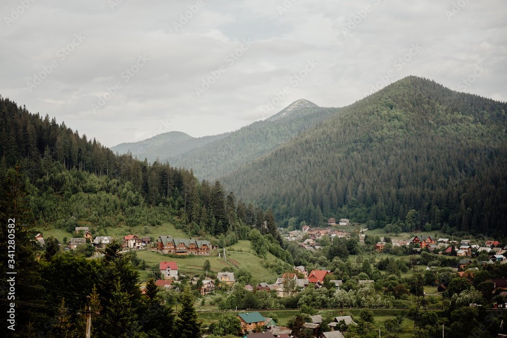 village in a mountain valley amid mountain peaks with a growing dense coniferous forest