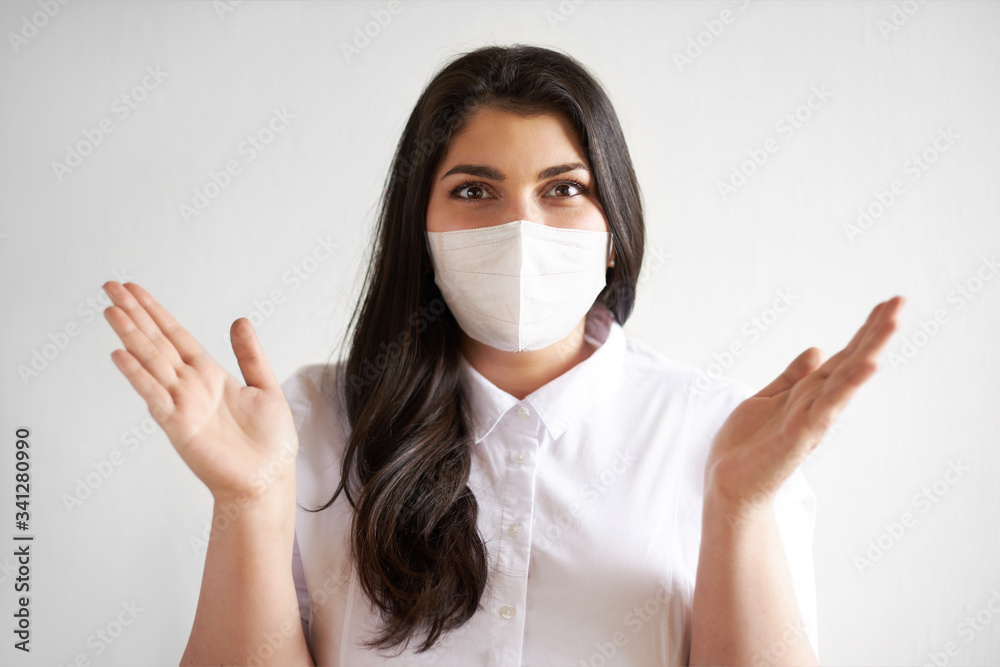 Dark haired female using disposable face protection to prevent spread of pandemic respiratory disease, keeping distance. Young woman wearing surgical mask against air pollution or industrial emission Dark haired female using disposable face protection to prevent spread of pandemic respiratory disease, keeping distance. Young woman wearing surgical mask against air pollution or industrial emission