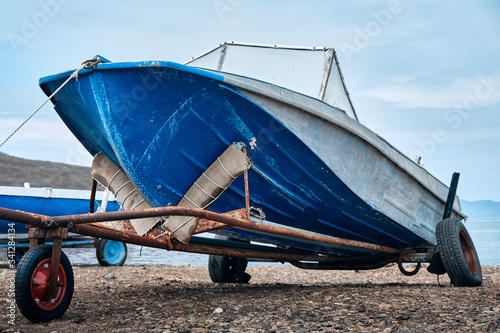 Old fishing blue speed boat put out of the sea. Low wide angle view
