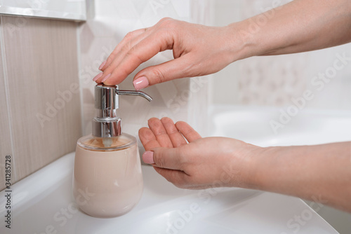 Woman washing hands with liquid soap at home. Coronavirus prevention