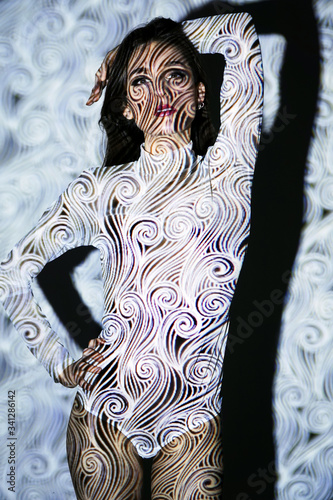 Obraz na plátně Young woman in studio with artistic projection from slide projector looks as if