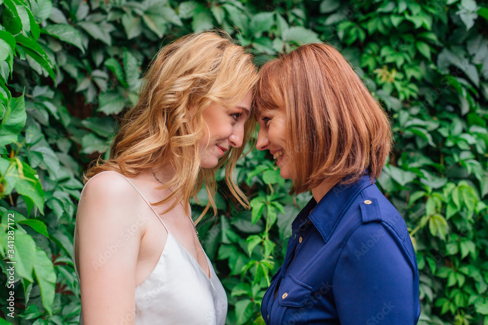 Beautiful mother and her grown up daughter standing head to head to each other on a summer day outside Beautiful mother and her grown up daughter standing head to head to each other on a summer day outside
