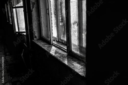 black and white photo with noise and film grain. abandoned hotel building. old broken windows. horror interior
