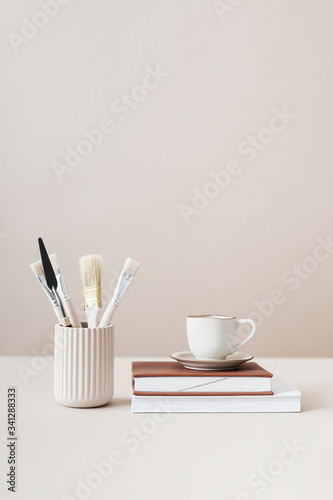 Paintbrushes and cup on top of books