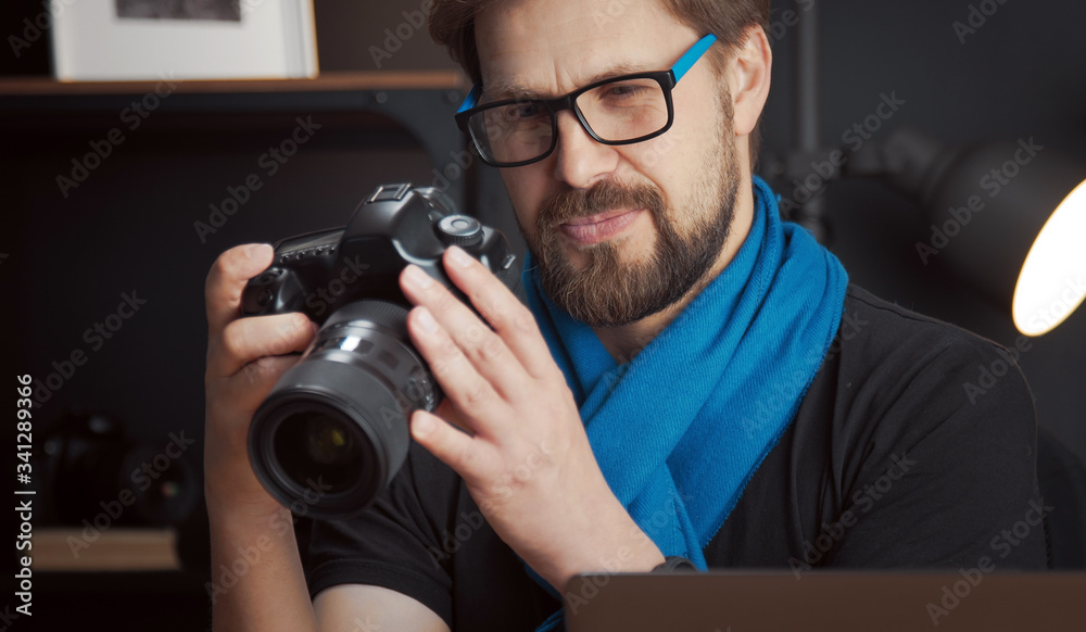 Close-up of joyful mature male photographer reviewing pictures in DSLR camera staying in studio Close-up of joyful mature male photographer reviewing pictures in DSLR camera staying in studio
