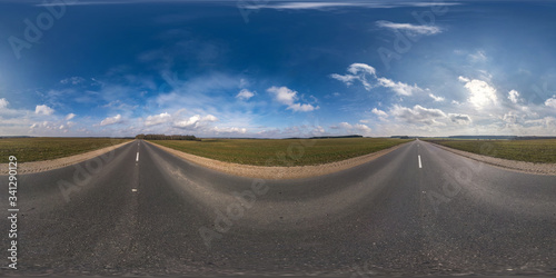 Full spherical seamless panorama 360 degrees angle view on no traffic asphalt road among fields in evening  before sunset with cloudy sky. 360 panorama in equirectangular projection  VR AR content