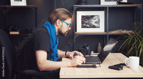Side view of professional photographer retouching pictures working in photo editing application