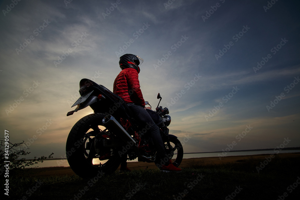 
young man with a motorcycle at sunset