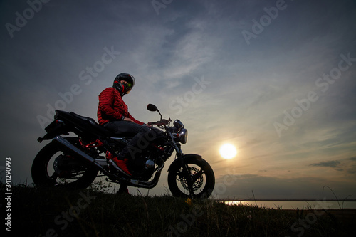  young man with a motorcycle at sunset