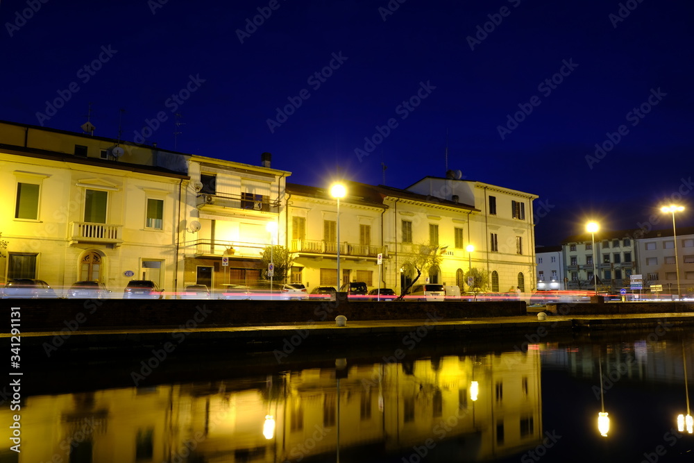 Casa illuminata di notte e riflessa nel canale del mare, porto a Viareggio 