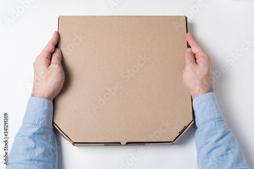 Box of pizza in male hands. White background. Concept of food delivery to home. Top view © somemeans