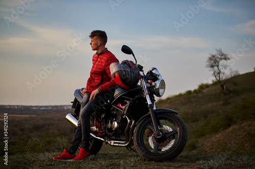 young man with a motorcycle at sunset