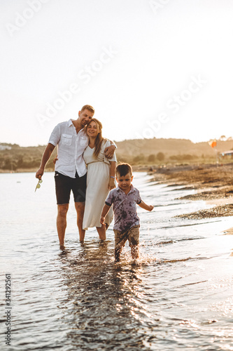 stylish man and his wife and their little son relaxing by the sea at sunset. Photo from a real family home album, their memories of a vacation on the sea