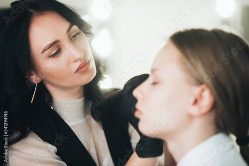 Dyeing and shaping of eyebrows. girl in a beauty salon. plucking eyebrows with tweezers