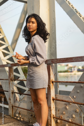 A young beautiful girl poses on an old bridge.