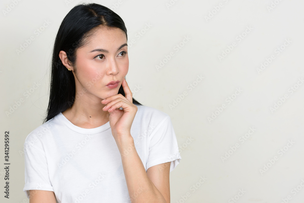 Portrait of young beautiful Asian woman thinking and looking up Portrait of young beautiful Asian woman thinking and looking up