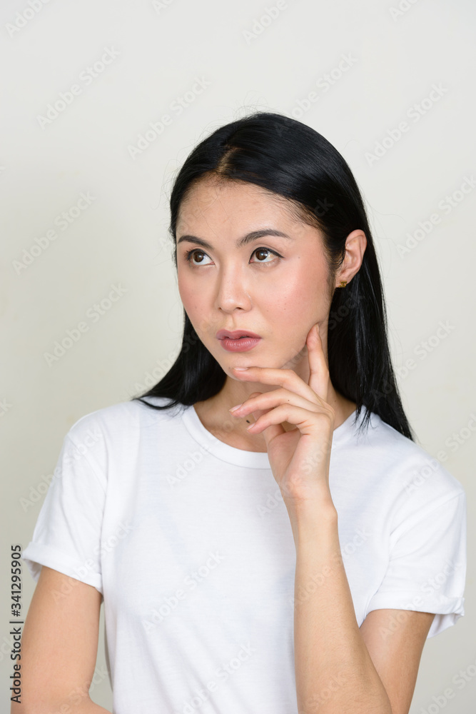 Portrait of young beautiful Asian woman thinking and looking up Portrait of young beautiful Asian woman thinking and looking up