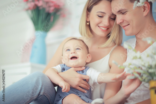 baby with parents in a cozy house / healthy young family mom dad and baby, happiness smile