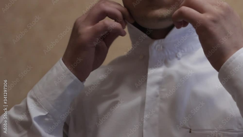 a man puts a bow tie around his neck a man puts a bow tie around his neck