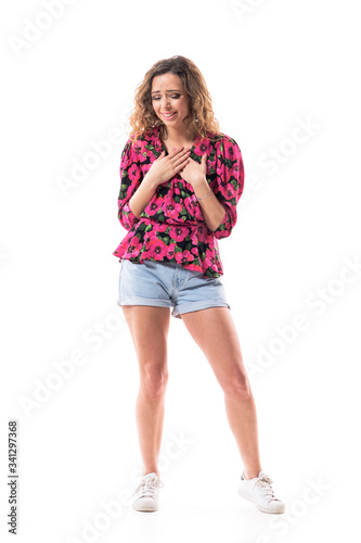 Overwhelmed touched emotional young pretty woman looking down in compassion seeing something cute. Full body isolated on white background. 