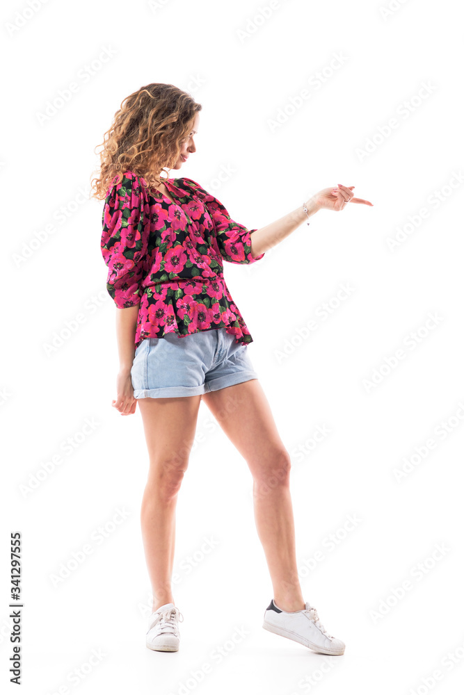 Side view of stylish happy curly hair girl in summer clothes pointing finger and advertising. Full body isolated on white background. Side view of stylish happy curly hair girl in summer clothes pointing finger and advertising. Full body isolated on white background.