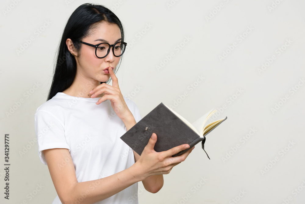Young beautiful Asian nerd woman reading book with eyeglasses Young beautiful Asian nerd woman reading book with eyeglasses