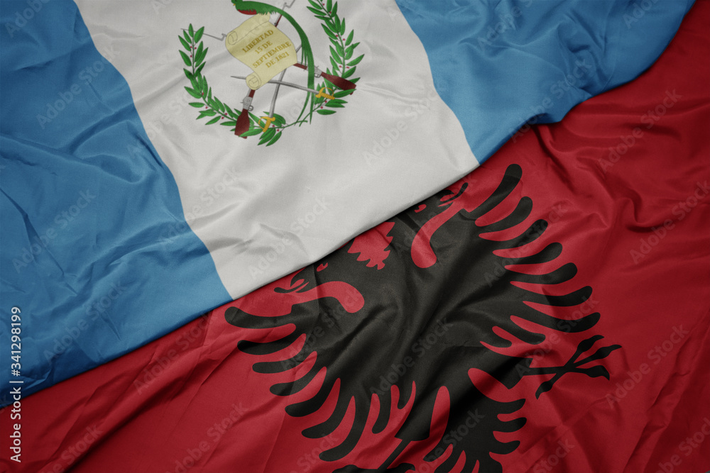 waving colorful flag of albania and national flag of guatemala.