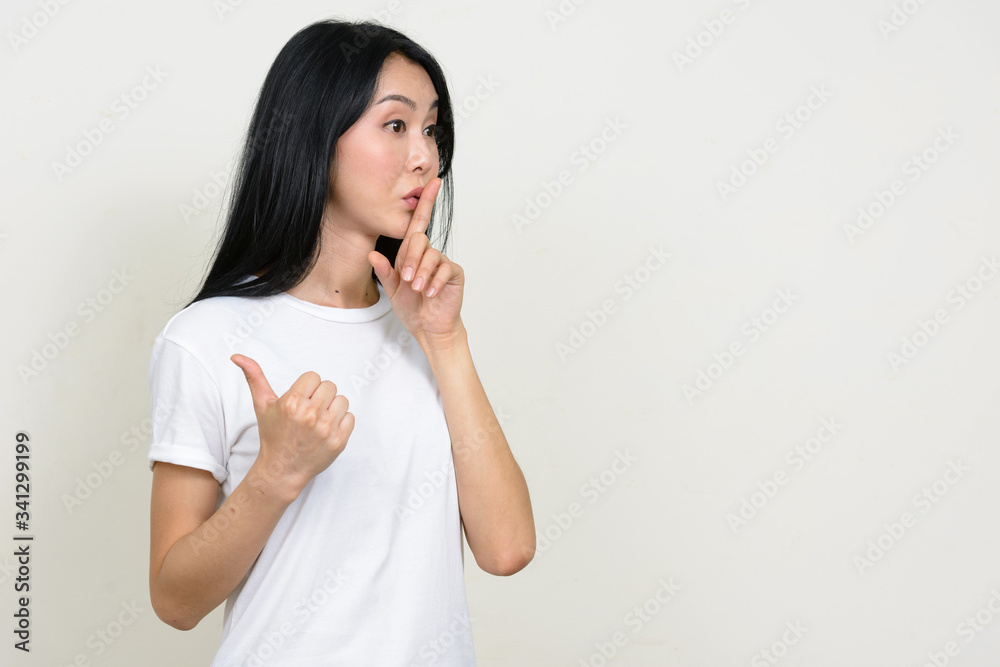 Portrait of young Asian woman gossiping with finger on lips Portrait of young Asian woman gossiping with finger on lips