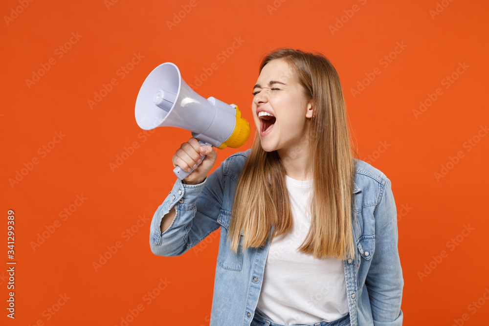 Crazy young woman girl in casual denim clothes posing isolated on orange wall background studio portrait. People lifestyle concept. Mock up copy space. Screaming in megaphone, keeping eyes closed. Crazy young woman girl in casual denim clothes posing isolated on orange wall background studio portrait. People lifestyle concept. Mock up copy space. Screaming in megaphone, keeping eyes closed.