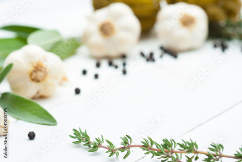 raw tagliatelle pasta, garlic and spice leaves on white wood table background