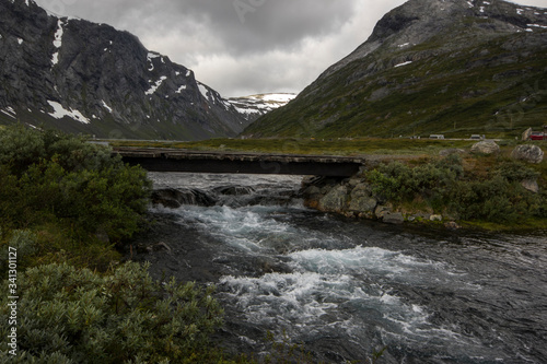  Norway. Wooden bridge over a mountain river and mountains in the background