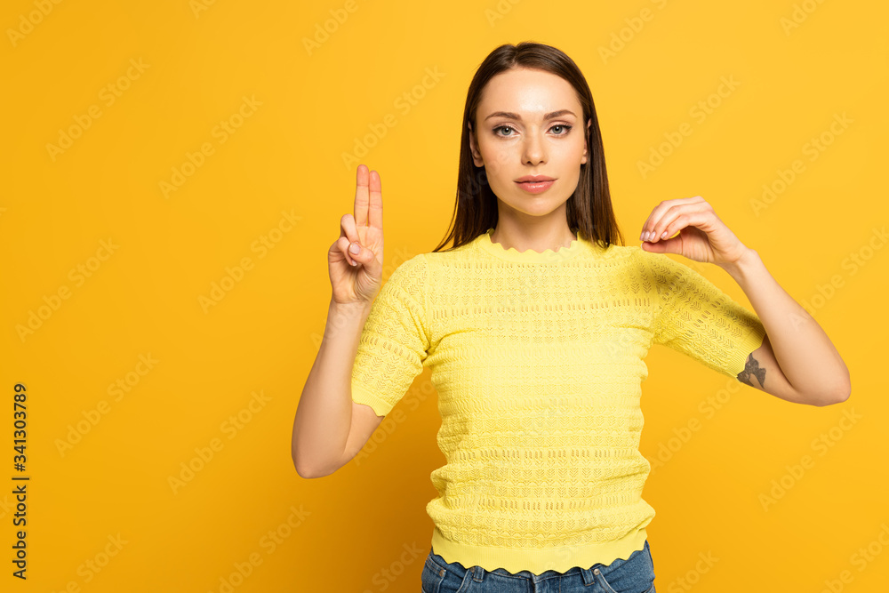 Woman showing letters in deaf and dumb language on yellow background Woman showing letters in deaf and dumb language on yellow background