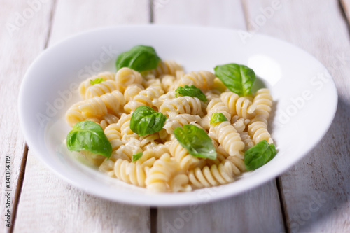 fusilli pasta with basil leaves and cheese close up on white rustic background
