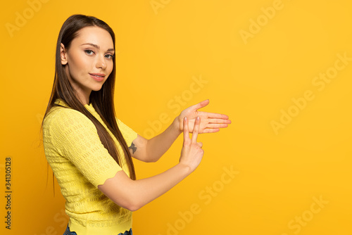Side view of woman showing gesture in deaf and dumb language on yellow background