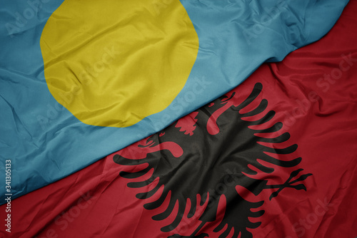 waving colorful flag of albania and national flag of Palau .