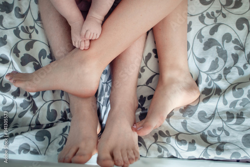 Husband and wife with a child lying  their legs are together.