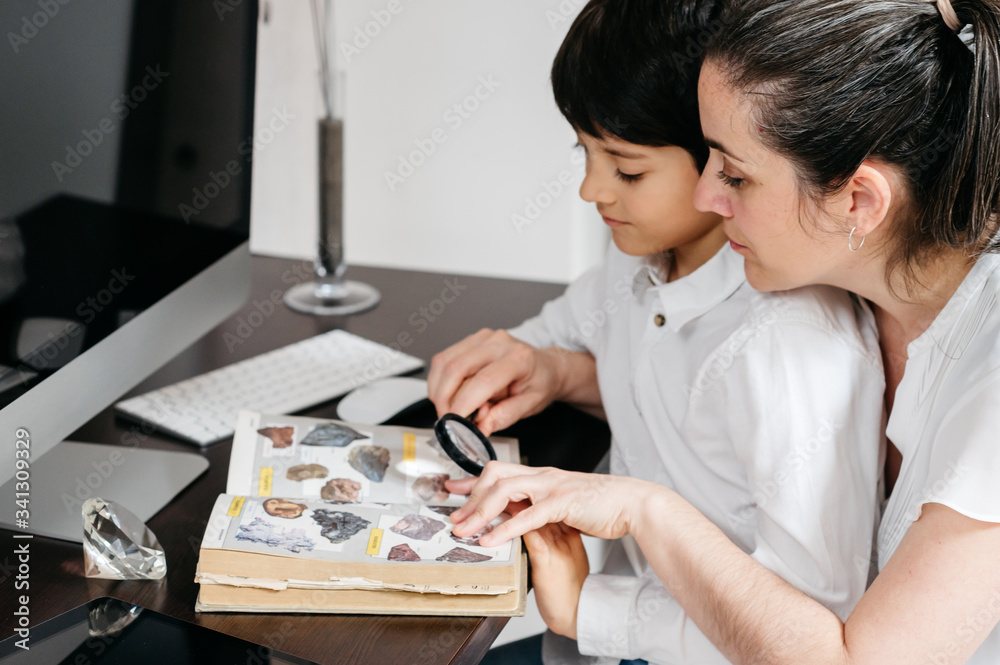 boy studying with his mature mother and looking through a magnifying glass boy studying with his mature mother and looking through a magnifying glass