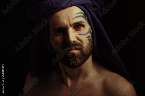 tattoo on the face, male portrait in the form of an assassin, cosplay, tattooed brutal man, guy with a tattooed face