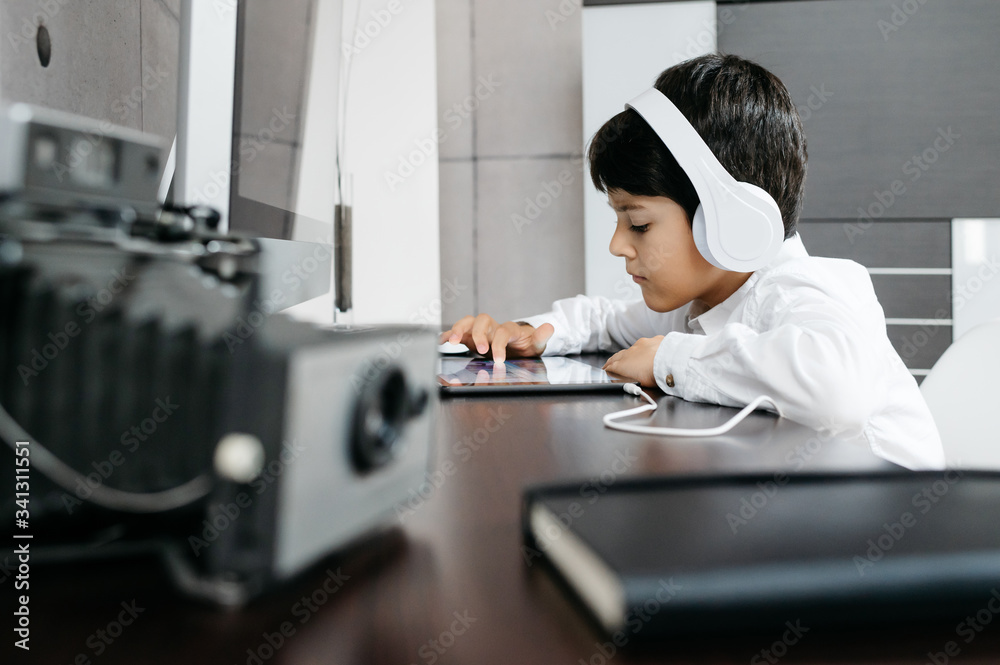 A person standing in front of a computer with white headphones and touching a tablet A person standing in front of a computer with white headphones and touching a tablet