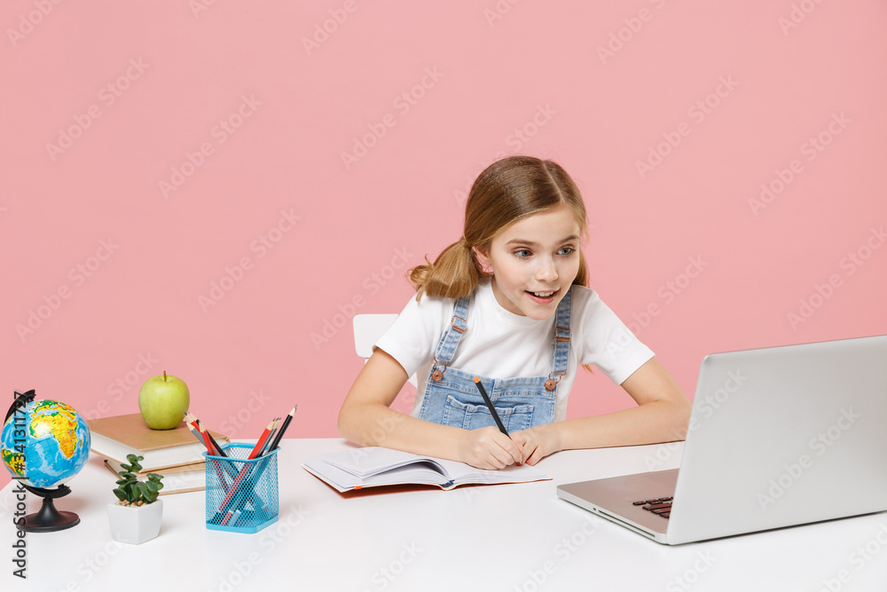 Pretty little kid schoolgirl 1213 years old sit studying at white desk